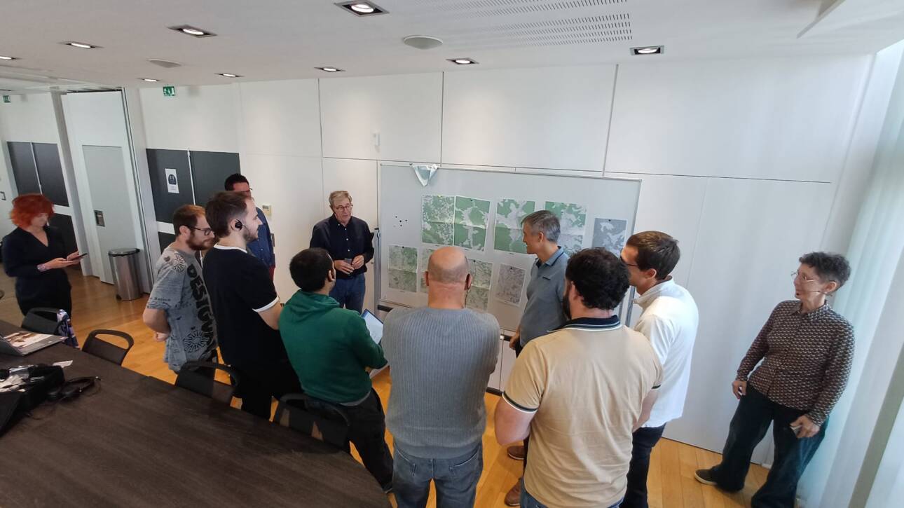 Reunión técnica del proyecto AI4Flood en Urrugne donde los socios analizan mapas y datos de inundaciones para definir la arquitectura de datos, octubre 2025.